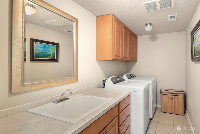 laundry room featuring cabinets, a textured ceiling, sink, separate washer and dryer, and light tile patterned flooring