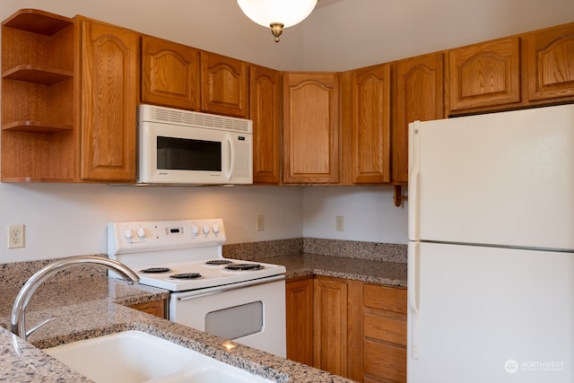 kitchen featuring white appliances, light stone countertops, and sink