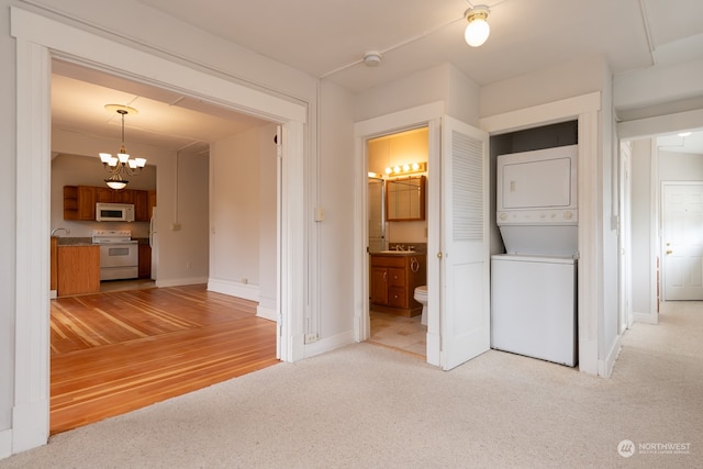 interior space with a notable chandelier, light carpet, and stacked washer and dryer