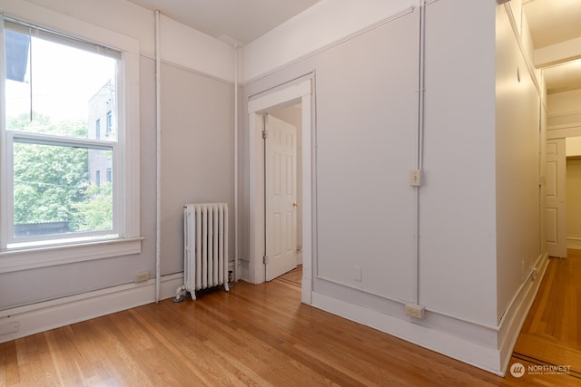 unfurnished bedroom with light hardwood / wood-style floors and radiator heating unit