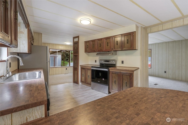 kitchen featuring sink, wooden walls, electric stove, and light wood-type flooring