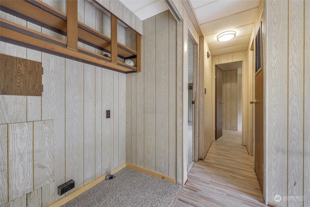 hall with light wood-type flooring and wooden walls