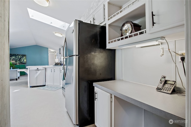 kitchen with light countertops, lofted ceiling with skylight, white cabinetry, and stainless steel appliances