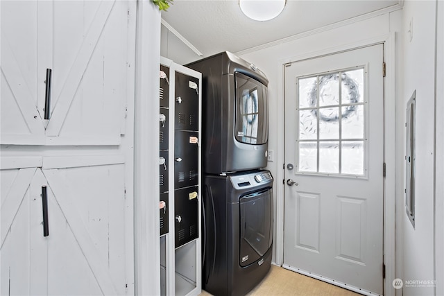 clothes washing area with stacked washer and clothes dryer, ornamental molding, and laundry area