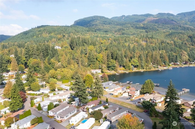 aerial view featuring a residential view, a water and mountain view, and a wooded view