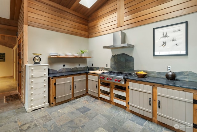 kitchen with lofted ceiling with skylight, stainless steel gas stovetop, wall chimney exhaust hood, and wood ceiling