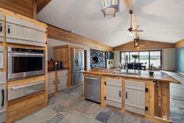 kitchen with wooden counters, sink, vaulted ceiling, ceiling fan, and stainless steel appliances