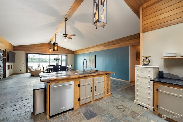 kitchen with wooden counters, lofted ceiling with beams, sink, stainless steel dishwasher, and ceiling fan