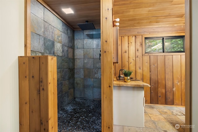 bathroom featuring tiled shower, wood walls, and wood ceiling