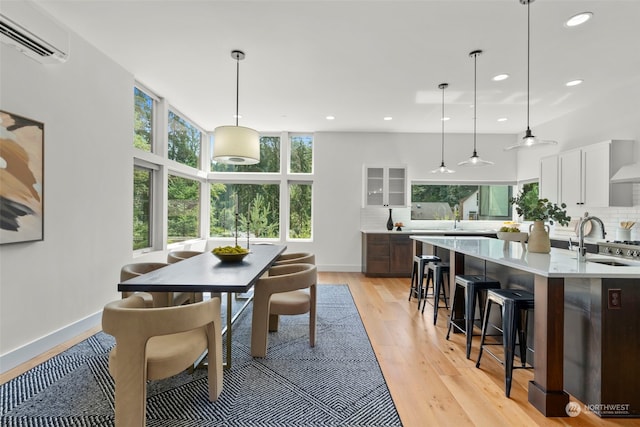 dining room featuring ceiling fan, light hardwood / wood-style flooring, sink, and a wall mounted air conditioner