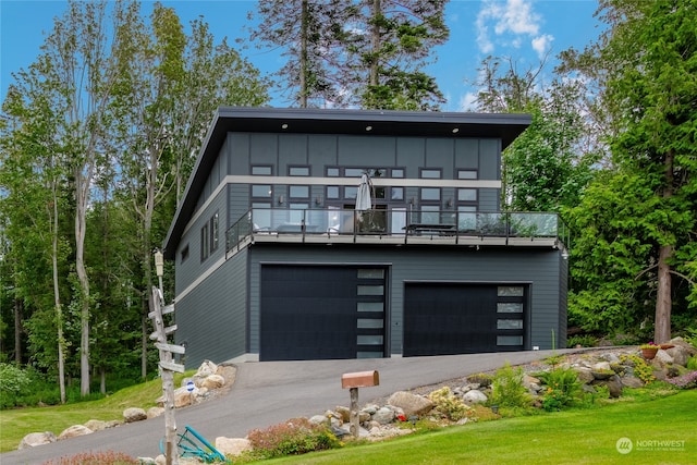 modern home featuring a balcony, a garage, and a front lawn