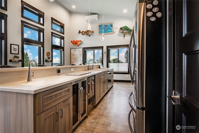 kitchen with sink, light wood-type flooring, light stone countertops, and a healthy amount of sunlight