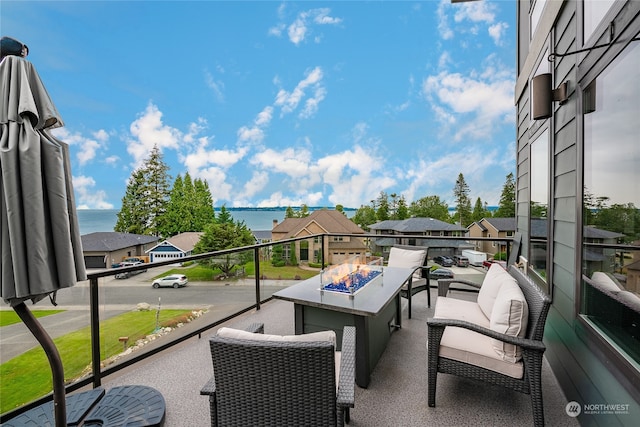 balcony with a water view and an outdoor fire pit