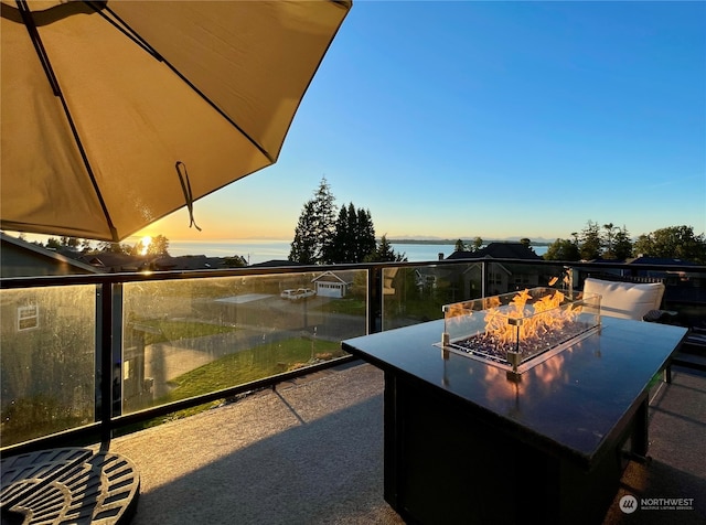 patio terrace at dusk featuring a water view and an outdoor fire pit