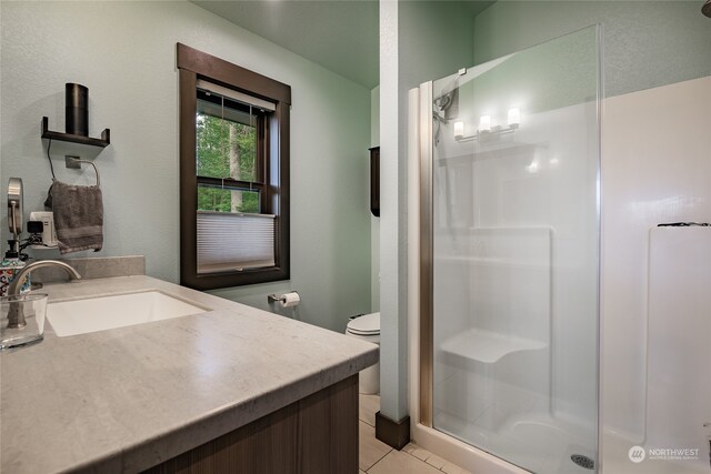 bathroom featuring vanity, a shower with door, tile patterned flooring, and toilet