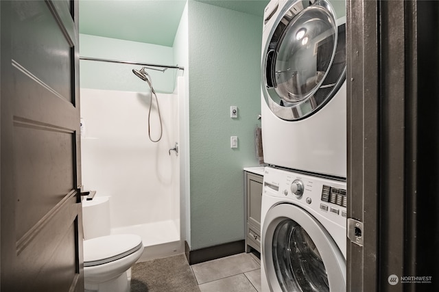 laundry room featuring stacked washer / drying machine and light tile patterned floors