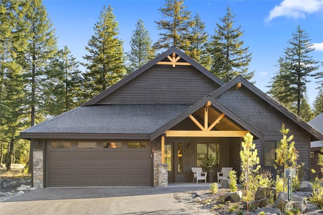 craftsman house with a porch, a garage, aphalt driveway, and stone siding