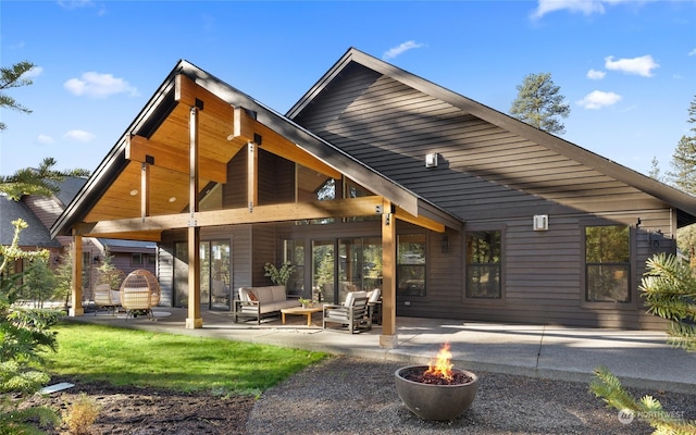 back of property with an outdoor living space with a fire pit and a patio area