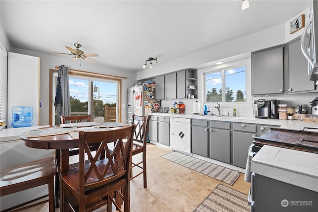 kitchen featuring white dishwasher, ceiling fan, gray cabinetry, and backsplash