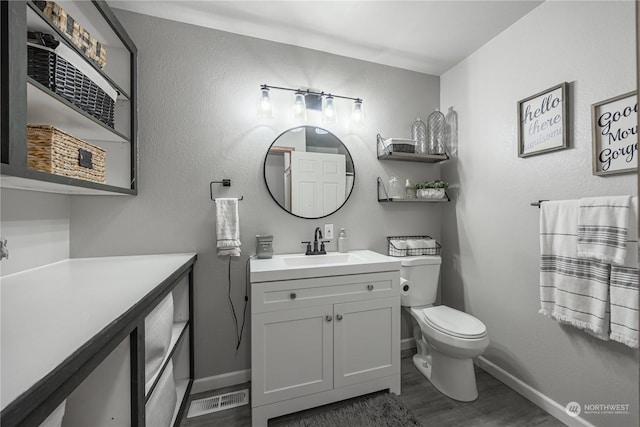 bathroom with toilet, vanity, and hardwood / wood-style flooring