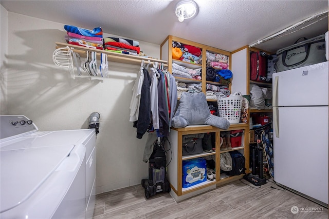 laundry room featuring wood-type flooring, a textured ceiling, and independent washer and dryer