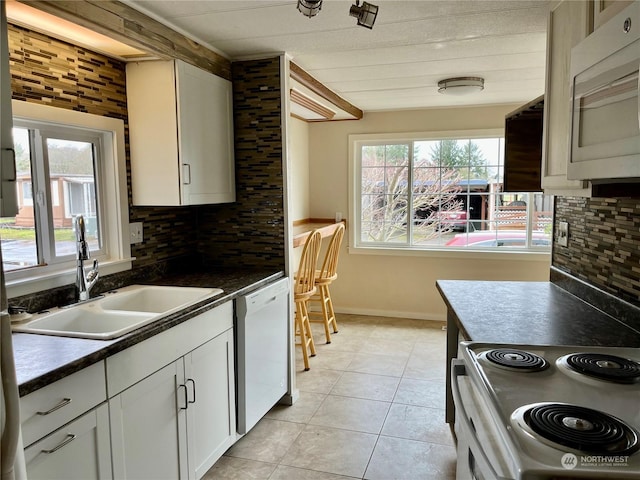 kitchen featuring a wealth of natural light, tasteful backsplash, white cabinetry, sink, and white appliances