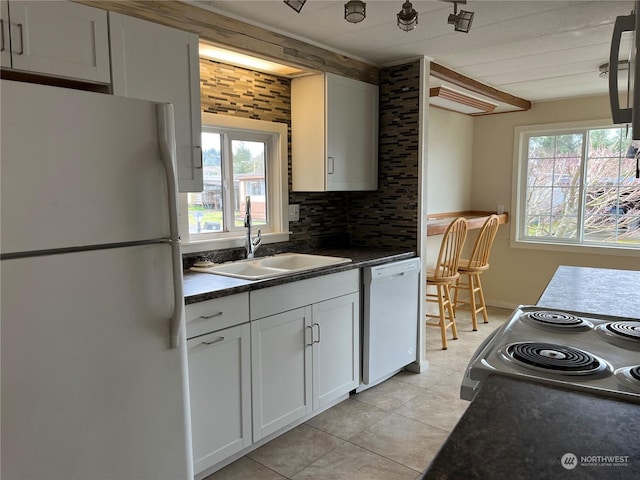 kitchen with sink, light tile patterned floors, white appliances, decorative backsplash, and white cabinets