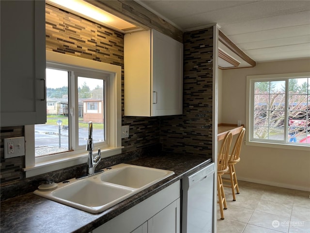 kitchen with tasteful backsplash, dishwasher, sink, and light tile patterned floors