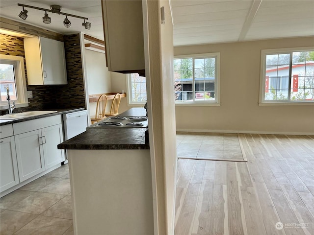 kitchen with tasteful backsplash, sink, white cabinets, black electric cooktop, and light hardwood / wood-style flooring