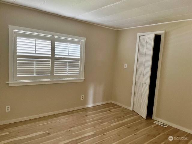 unfurnished bedroom with light hardwood / wood-style flooring and a closet