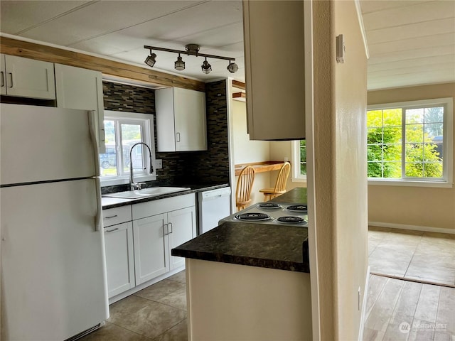 kitchen with light tile patterned flooring, white cabinetry, sink, decorative backsplash, and white appliances