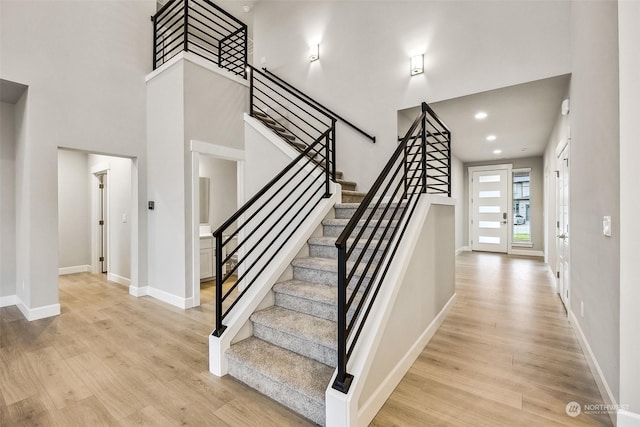 stairs with hardwood / wood-style floors and a high ceiling