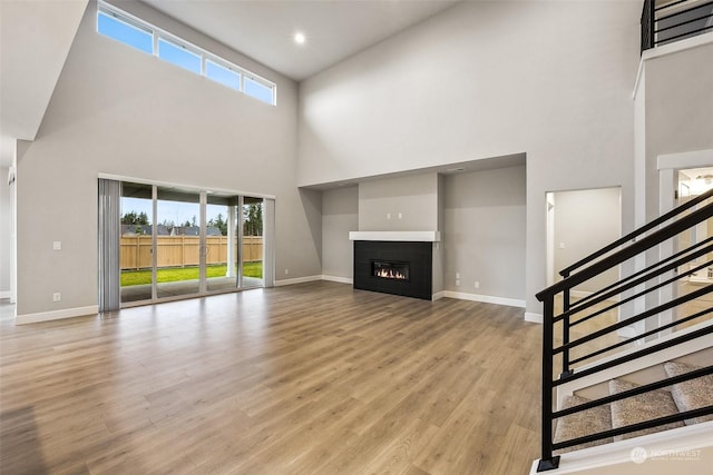 unfurnished living room with a high ceiling and light wood-type flooring