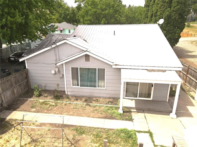 view of front facade featuring metal roof, a patio, and a fenced backyard