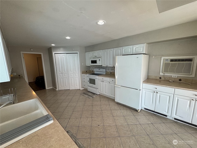 kitchen with white appliances, light tile flooring, a wall mounted air conditioner, backsplash, and white cabinets