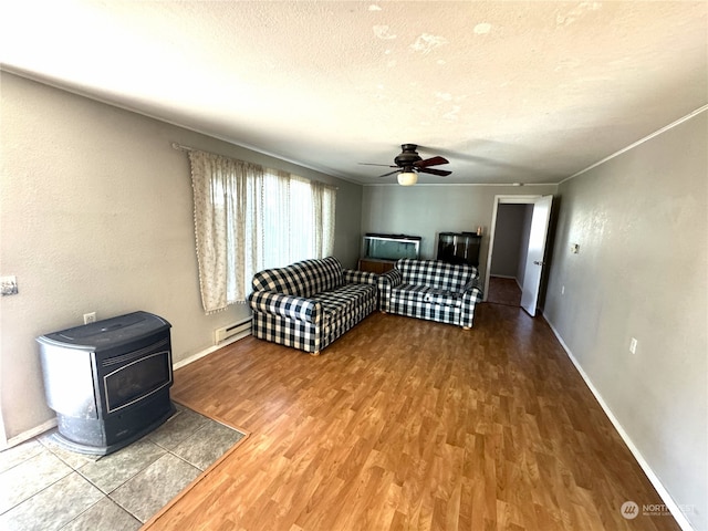 interior space featuring ceiling fan, hardwood / wood-style floors, a textured ceiling, a wood stove, and a baseboard heating unit