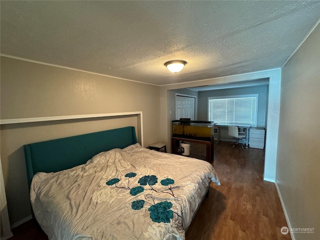 bedroom featuring baseboards, crown molding, a textured ceiling, and wood finished floors