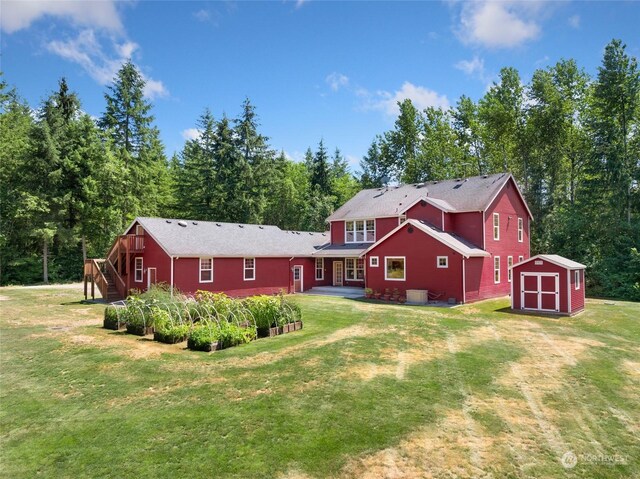 back of house featuring a yard and an outbuilding