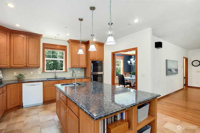 kitchen featuring dishwasher, a wealth of natural light, a kitchen island with sink, and light tile patterned floors