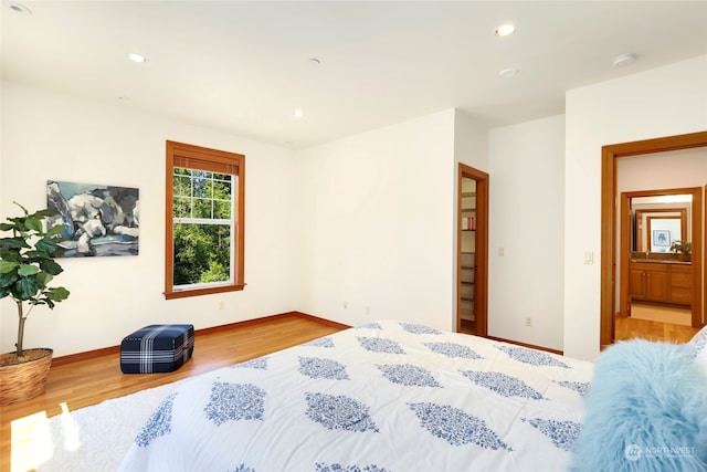 bedroom with light hardwood / wood-style floors and ensuite bath