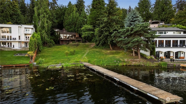 view of dock with a water view and a yard