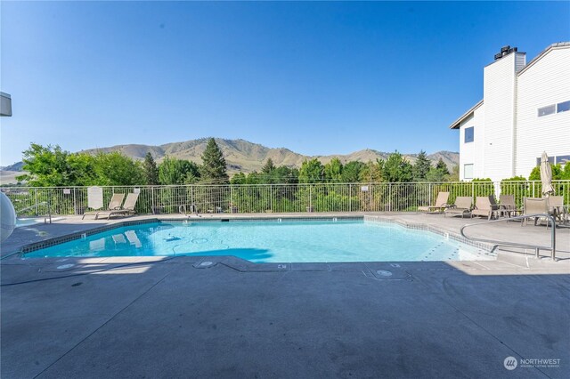 view of swimming pool with a mountain view and a patio area