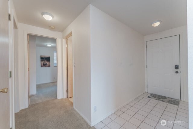 corridor featuring baseboards and light tile patterned flooring