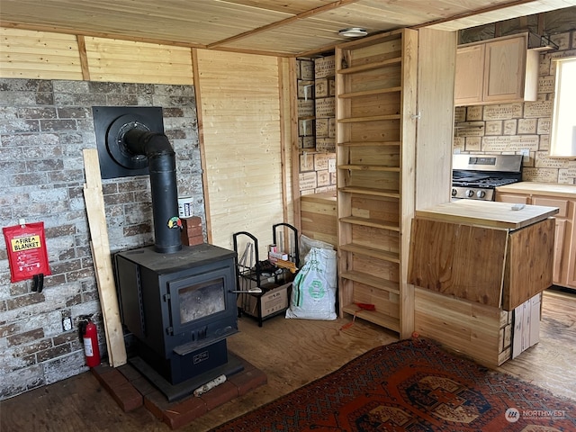 kitchen featuring wooden ceiling, hardwood / wood-style flooring, gas range, wood walls, and a wood stove