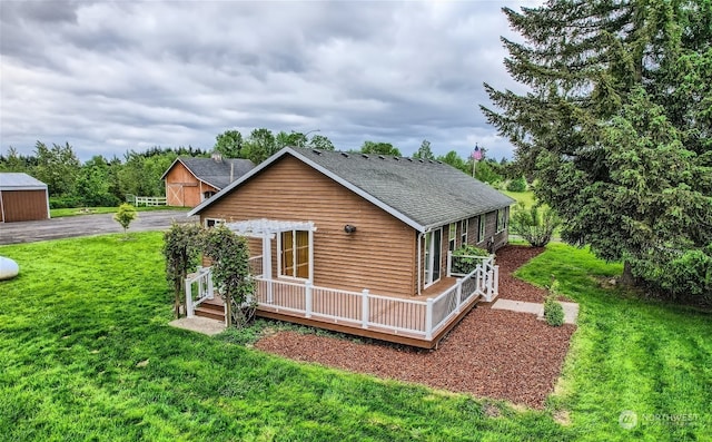 back of property featuring an outdoor structure and a lawn