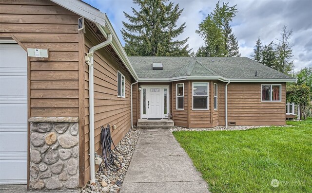 view of exterior entry featuring a garage and a yard