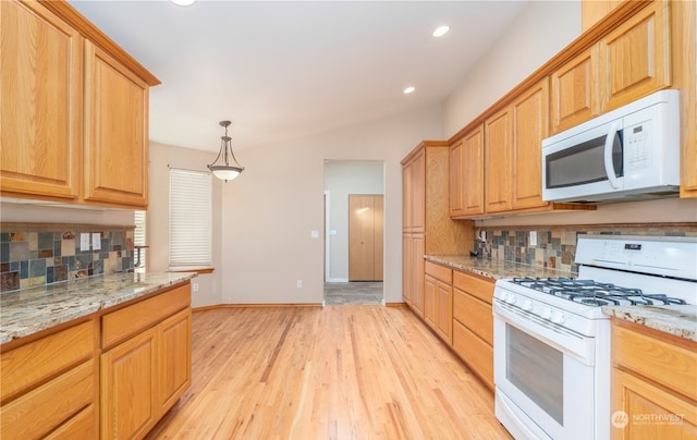 kitchen with light stone countertops, light wood-type flooring, white appliances, pendant lighting, and tasteful backsplash