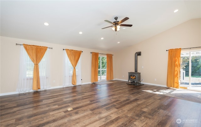 unfurnished living room featuring plenty of natural light, vaulted ceiling, ceiling fan, and a wood stove