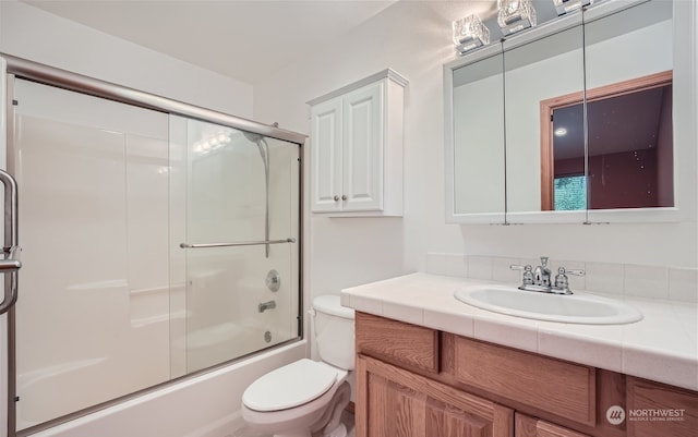 bathroom featuring enclosed tub / shower combo, toilet, and vanity