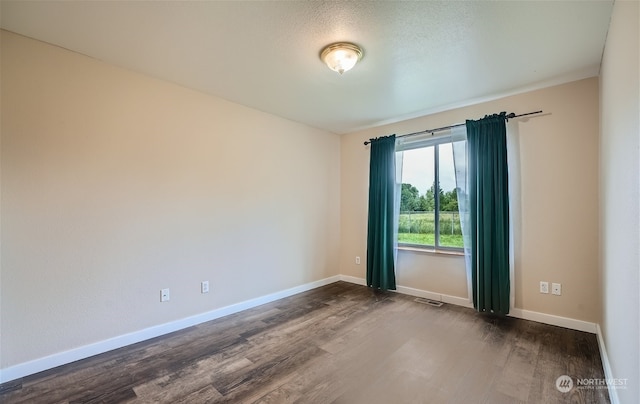 empty room with dark hardwood / wood-style floors and a textured ceiling